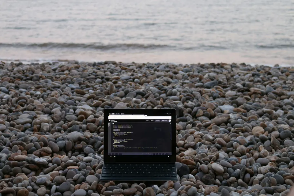Notebook aberto sobre seixos, de frente para o mar