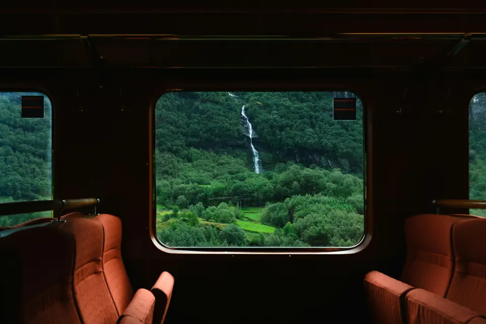 Cachoeira numa encosta verde vista pela janela de um trem antigo